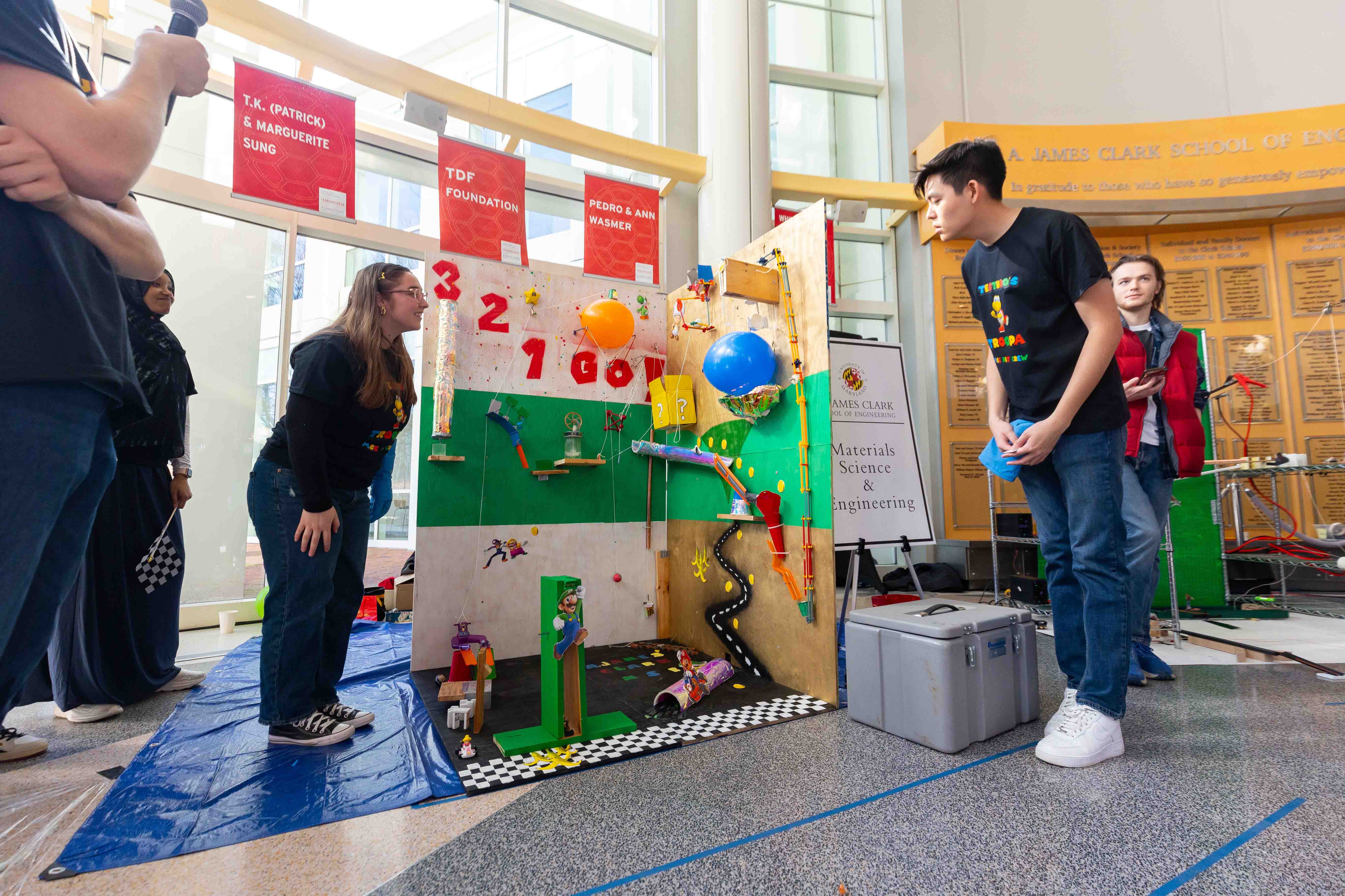 Two students standing next to a Rube Goldberg machine.