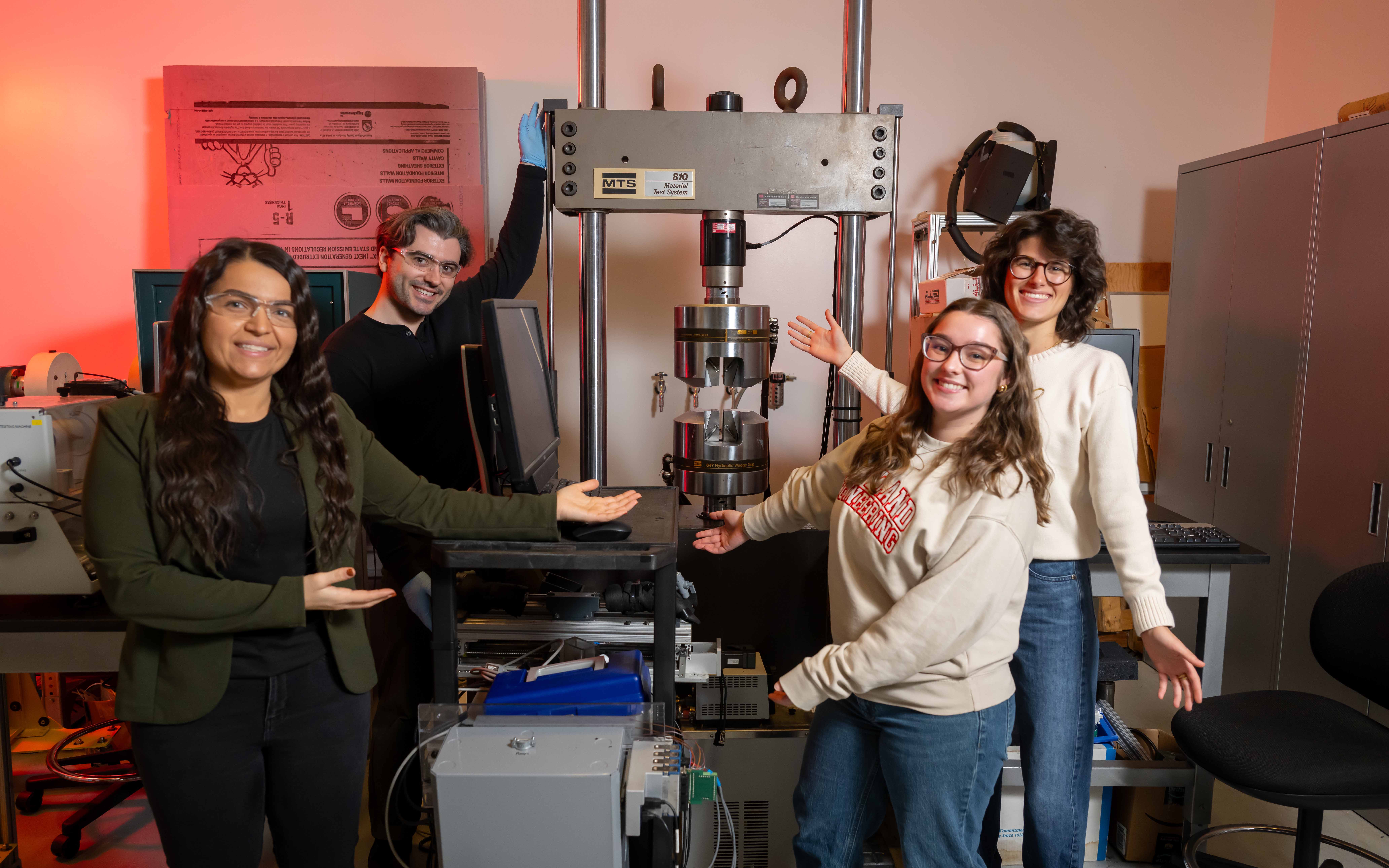 Professor and three students standing with lab equipment.