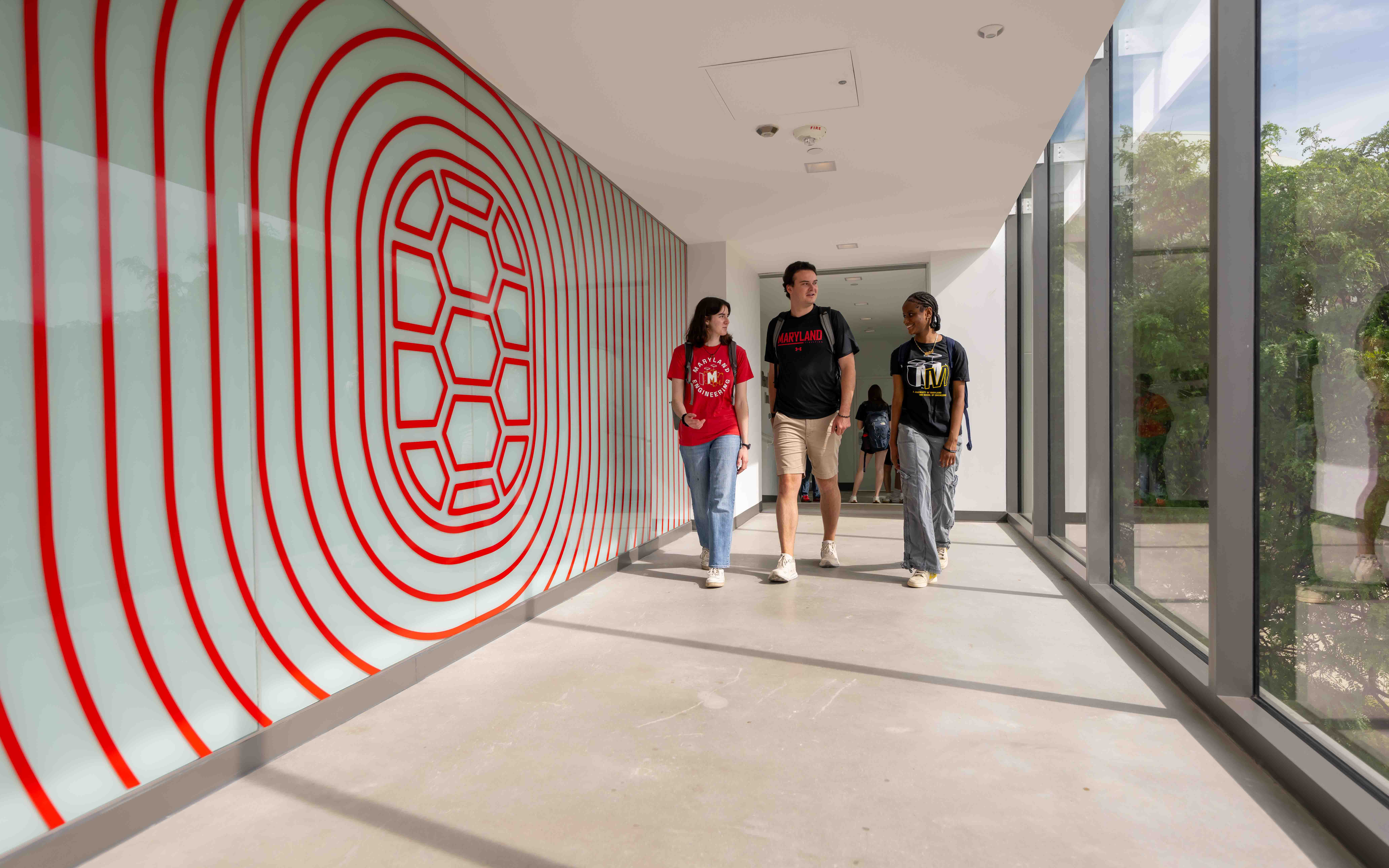Students walking down a hall with a Terrapin shell wallpaper.